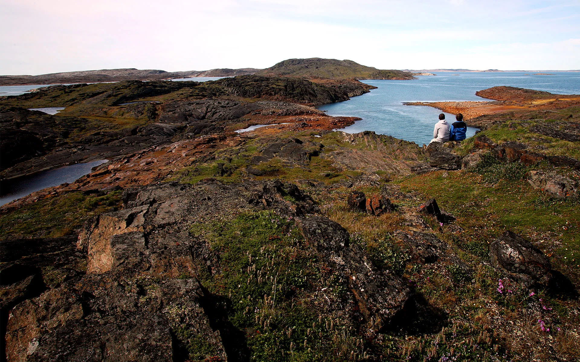 Two people walking across Nunavut landscape